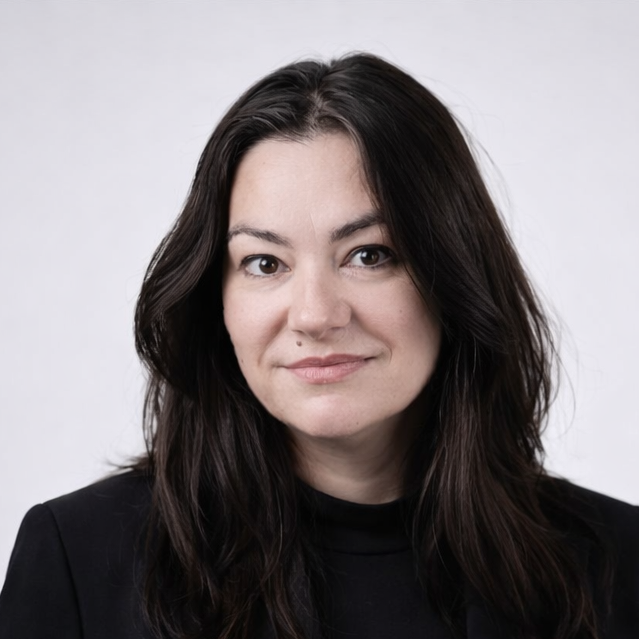 Portret Agnieszki Fujak na jasnym tle. Kobieta ma ciemne włosy i czarną marynarkę.
