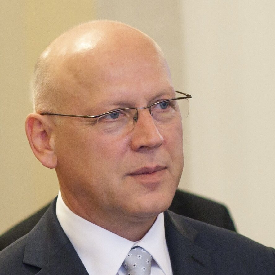 Portret mężczyzny w okularach, garniturze i krawacie.